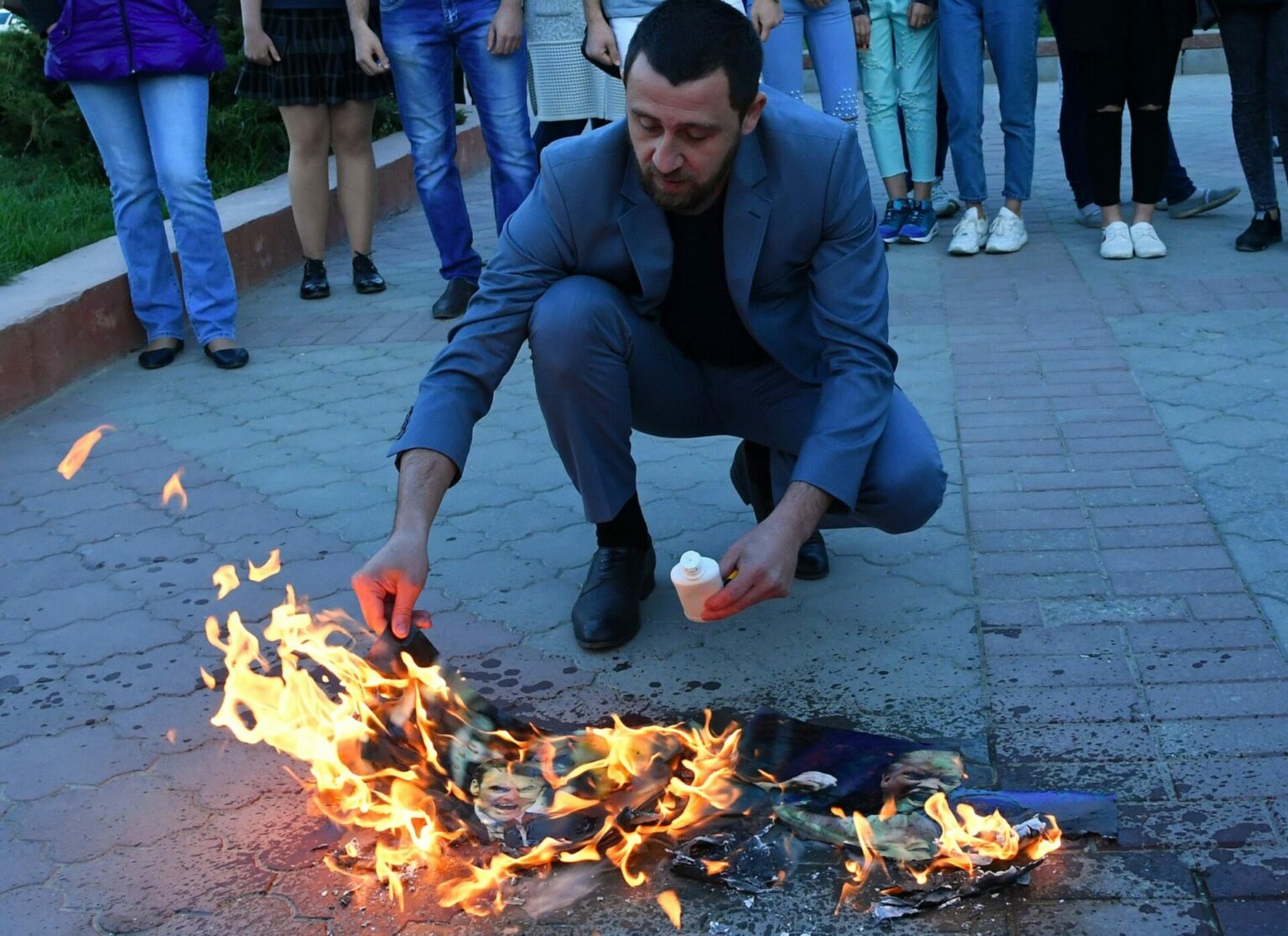 A participant in a protest in Simferopol against missile strikes on Syria burns images of US President Donald Trump, French President Emmanuel Macron and British Prime Minister Theresa May. Russian attitudes towards Donald Trump have changed since he took office.