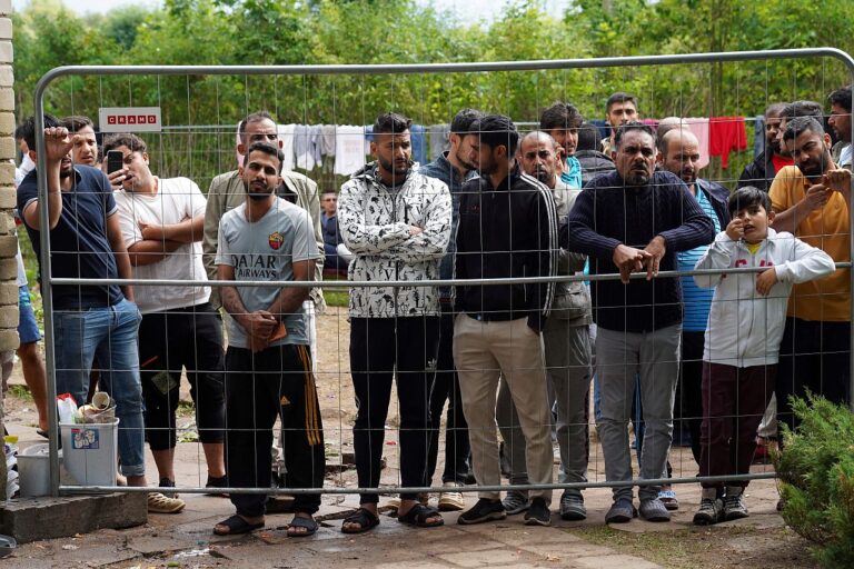 Migrants gather near a fence at a temporary detention center in Kazitiskis, Lithuania in August 2021.